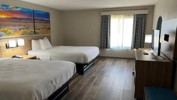 Quarto de hotel com duas camas, uma escrivaninha, uma televisão e um quadro de uma paisagem.