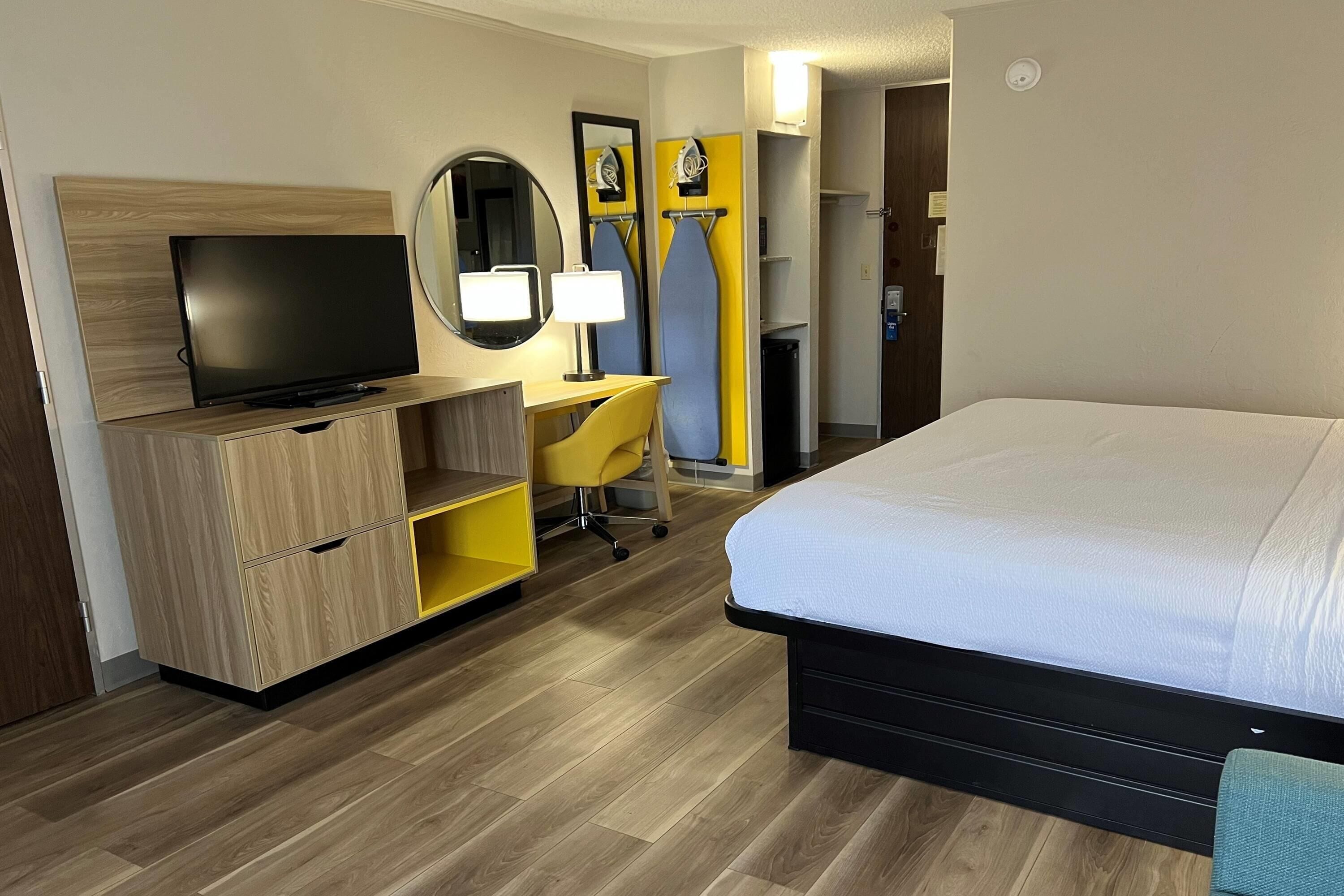 Une chambre d’hôtel comprenant un lit, une télévision, un bureau avec une chaise et une armoire.