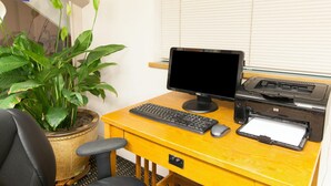 A wooden desk with a computer, keyboard, mouse, and printer. There is a potted plant on the desk. - Days Inn by Wyndham Norman (Norman)