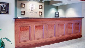 Een receptiebalie met een Comfort Inn bord, een ingelijste onderscheiding en een potplant.