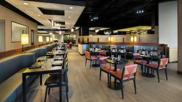 Un restaurant avec des banquettes et des tables, un coin bar et un long comptoir.