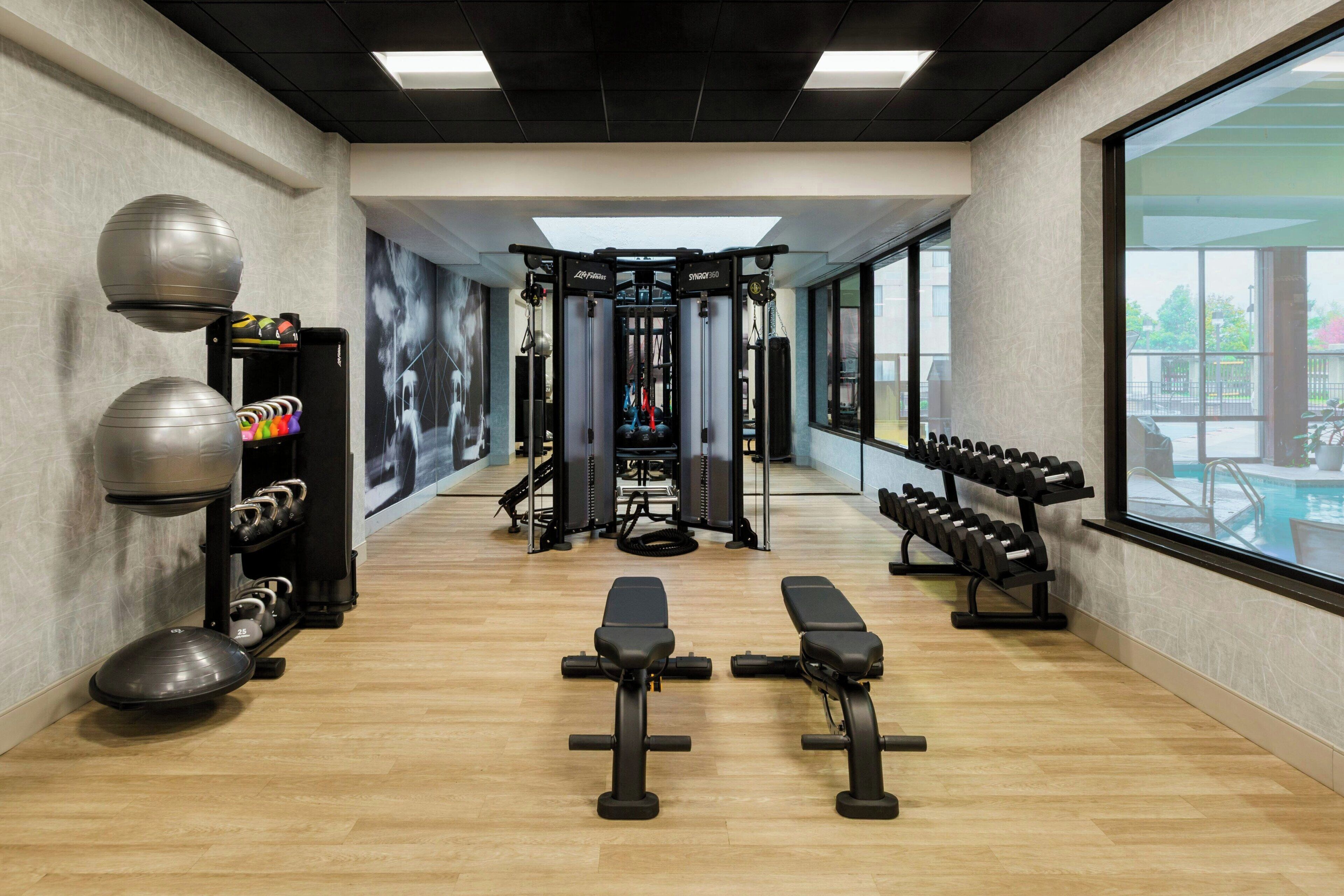 Uma academia com equipamentos de ginástica, bancos e um suporte na parede para halteres.
