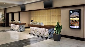 A hotel reception area with marble counters, a digital information screen, and a traditional patterned wall. - Buffalo Marriott Niagara (Buffalo)