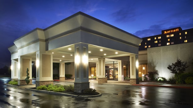 A Marriott hotel entrance with a covered outdoor area, a parking lot, and a building with illuminated windows. - Buffalo Marriott Niagara (Buffalo)