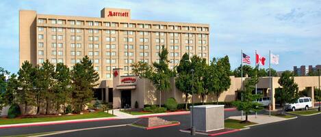A Marriott hotel with a large building, multiple flags, and a parking lot.