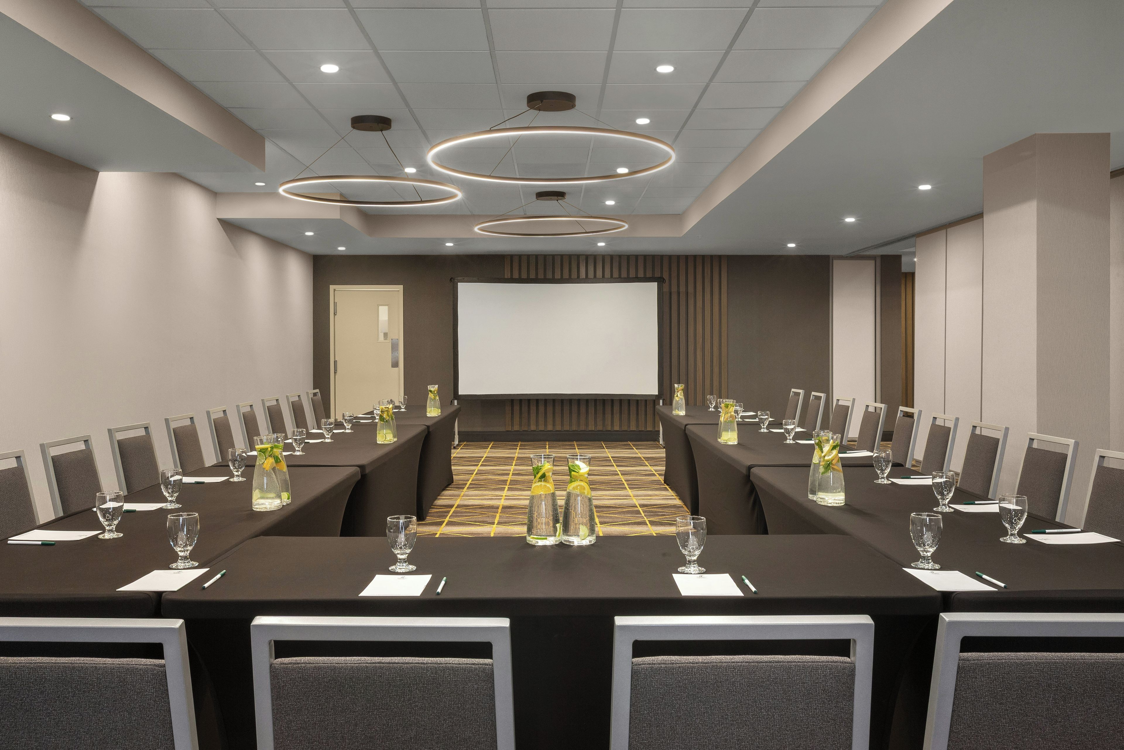 A conference room with a long table, chairs, a projector screen, and a whiteboard.