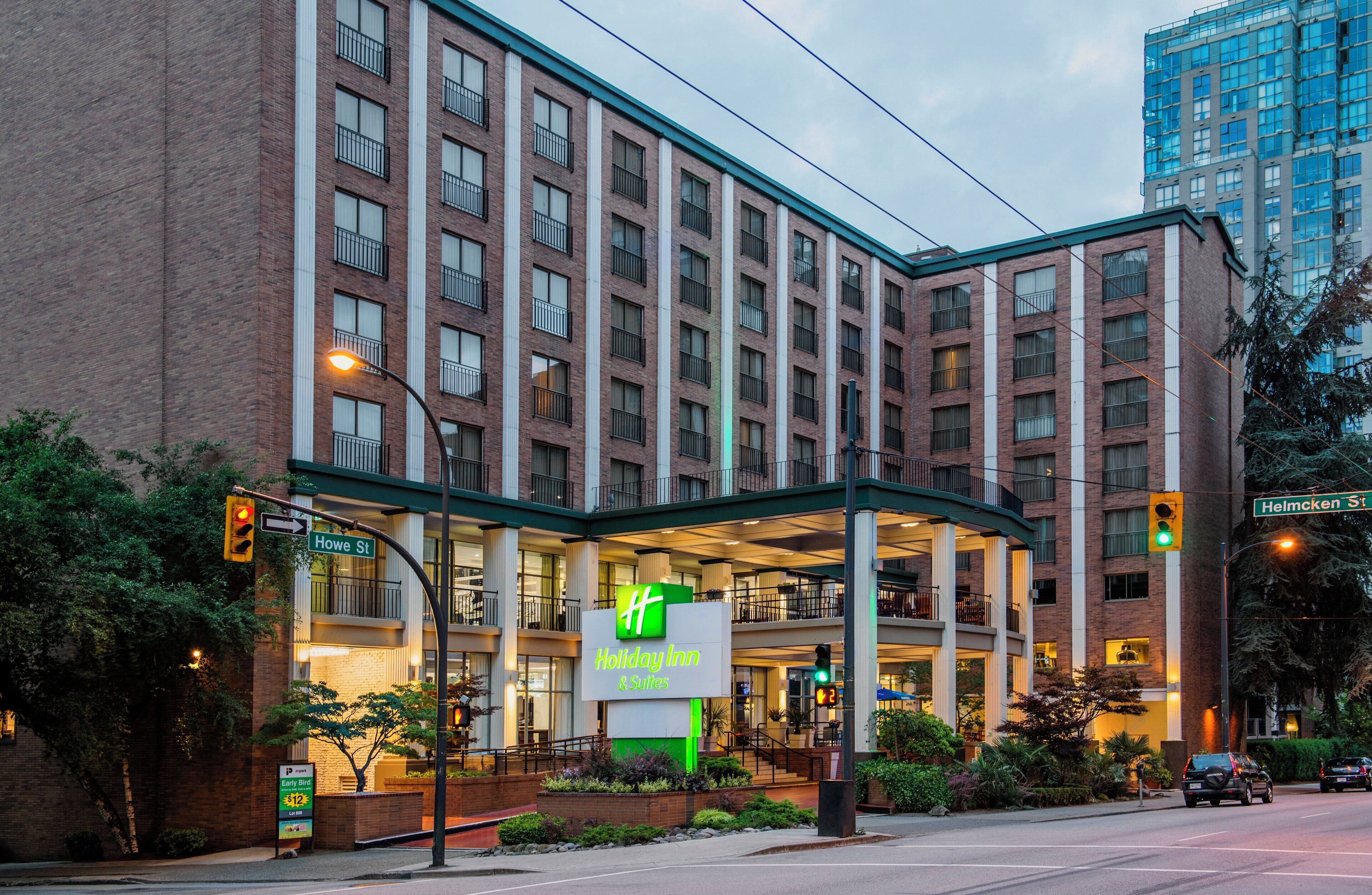 Un bâtiment de la chaîne Holiday Inn & Suites, avec une façade en briques, plusieurs étages et un espace d’entrée abrité doté de sièges extérieurs.