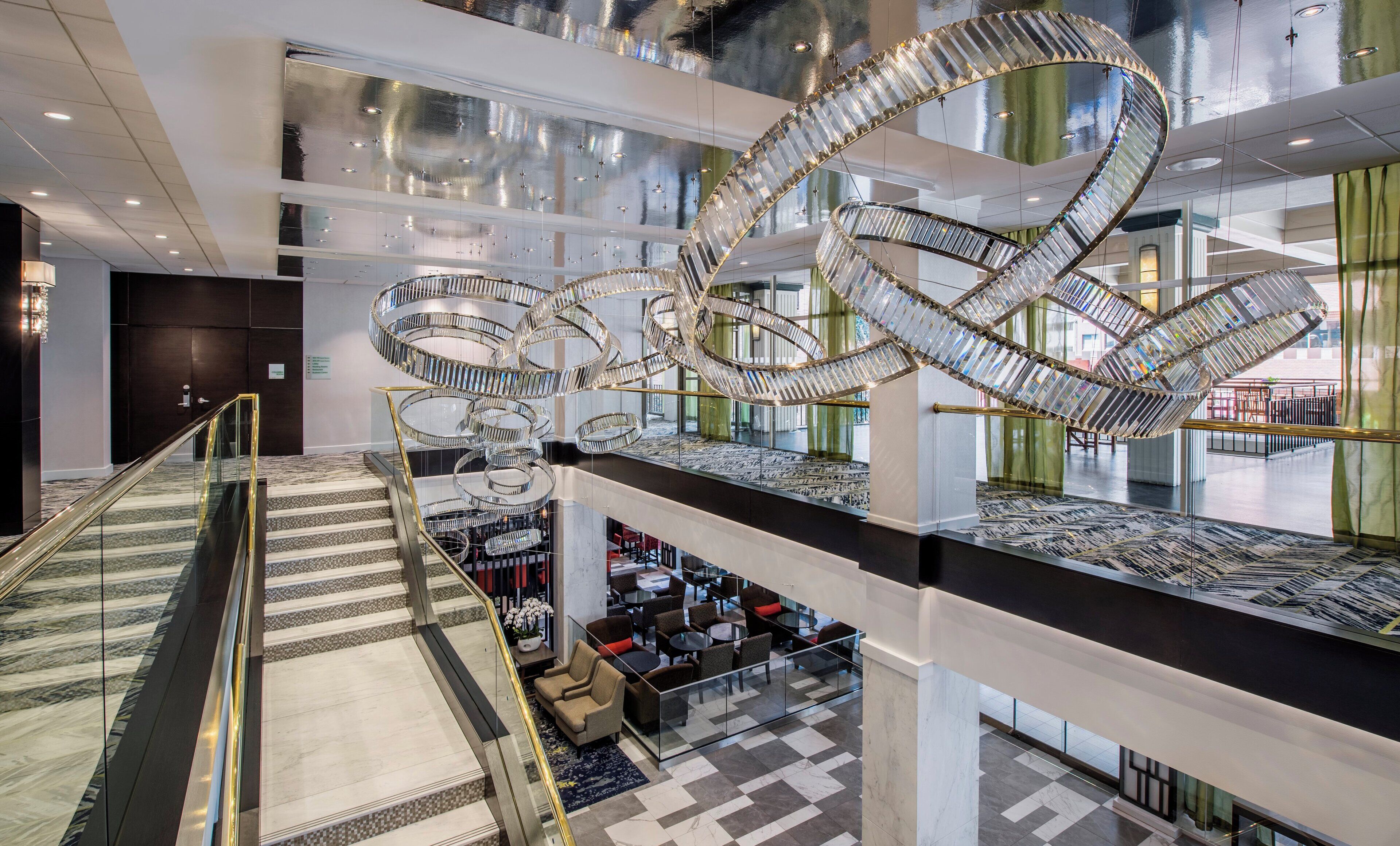 A modern hotel lobby with a central spiral staircase, multiple levels, and a glass railing.