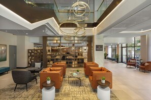 A spacious lobby with a modern chandelier, seating area, and a bar/lounge with a view. - Holiday Inn & Suites Vancouver Downtown by IHG (Vancouver)
