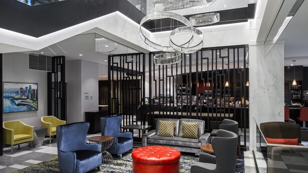A modern lobby with seating arrangements, a bar area, and a cityscape painting on the wall. - Holiday Inn & Suites Vancouver Downtown by IHG (Vancouver)