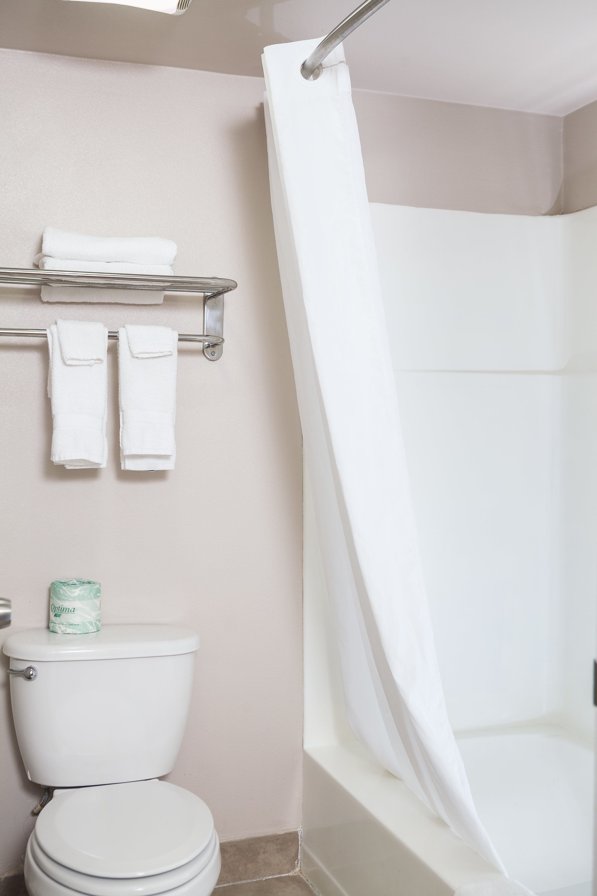 Un baño con inodoro, cortina de ducha y toallero con dos toallas.