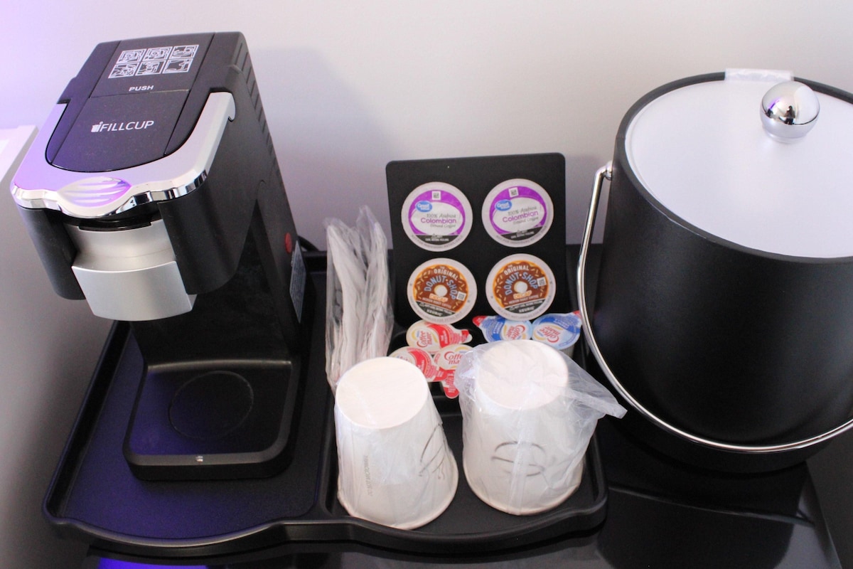 A coffee machine, a tray with coffee pods, and a coffee pot on a counter.