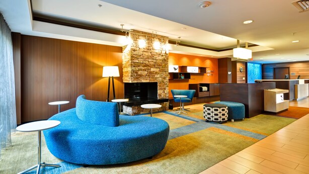 A modern hotel lobby with a stone fireplace, blue seating, and a reception desk. - Fairfield Inn & Suites Dallas Medical/Market Center (Dallas)