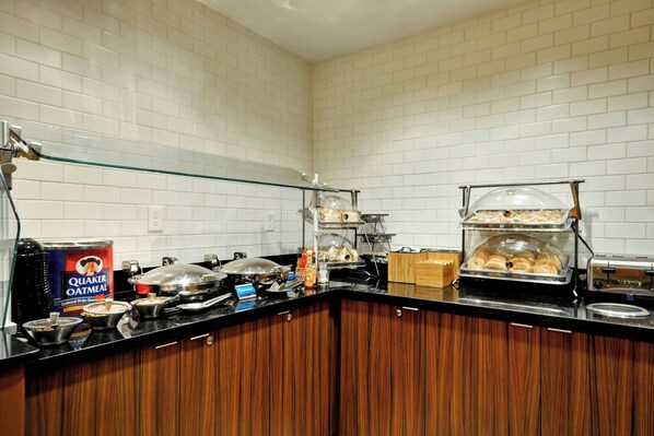 A breakfast buffet with Quaker Oatmeal, various hot dishes, and a variety of pastries.