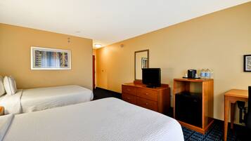 A hotel room with two beds, a wooden dresser, a television, and a desk with a chair.