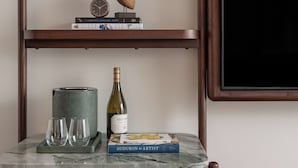 A wooden shelf with books, a wine bottle, and glasses. - The Greenleigh, River Oaks, Autograph Collection (Houston)