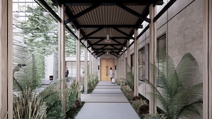 A covered walkway with a wooden ceiling, flanked by large windows and indoor plants. - The Greenleigh, River Oaks, Autograph Collection (Houston)