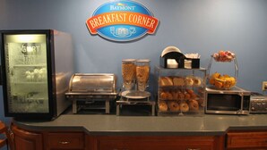 A breakfast station with a yogurt dispenser, a coffee machine, a fruit bowl, and a microwave. - Baymont Inn & Suites by Wyndham Lafayette/Purdue Area (Lafayette)