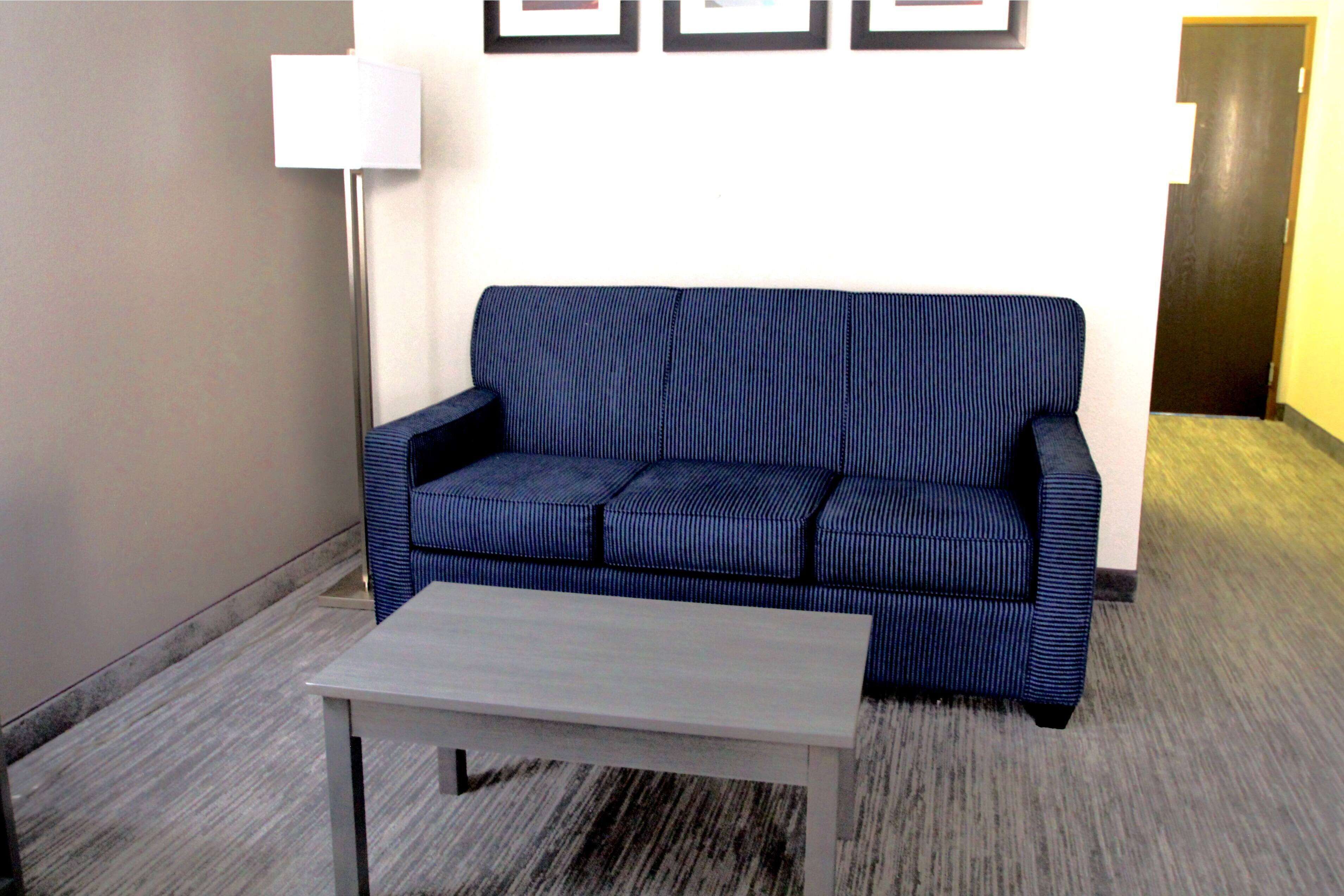 A room with a blue sofa, a white coffee table, and a lamp.