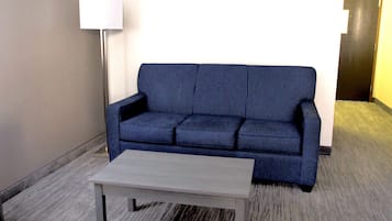 A room with a blue sofa, a white coffee table, and a lamp.