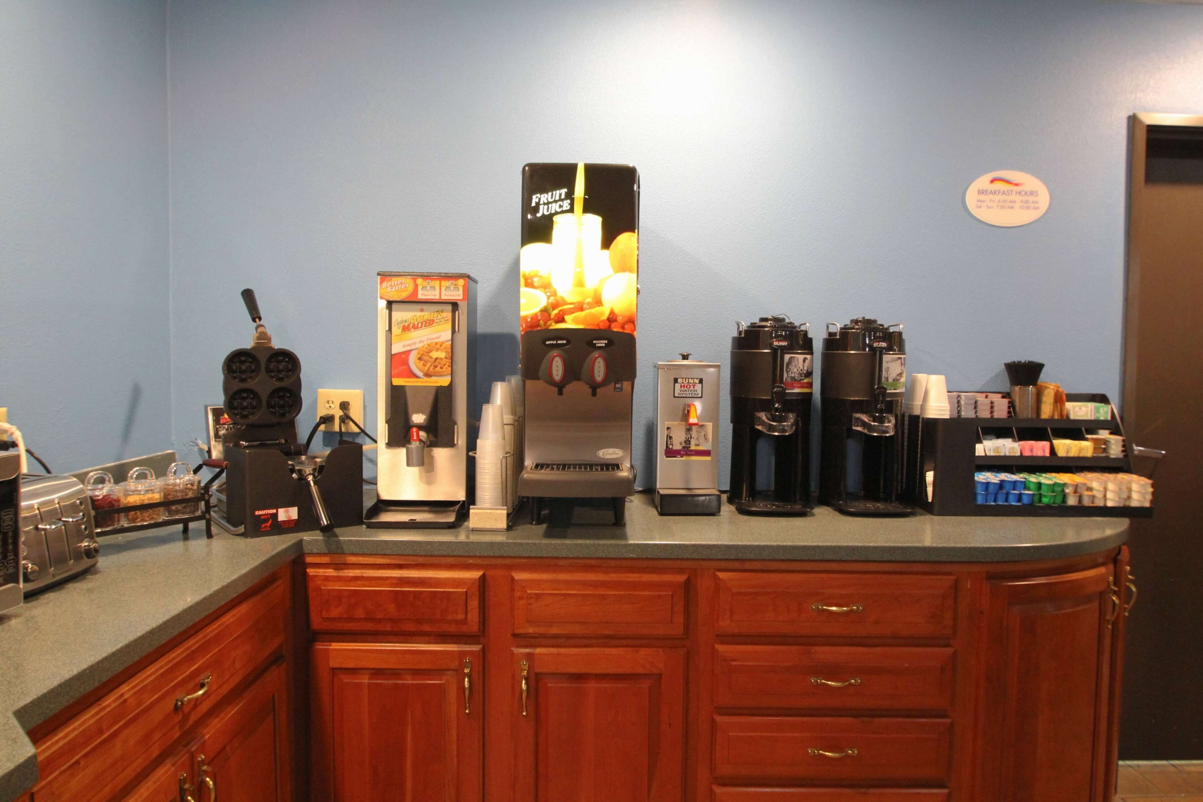 Una estación de café con varias máquinas de café y un dispensador de jugo.