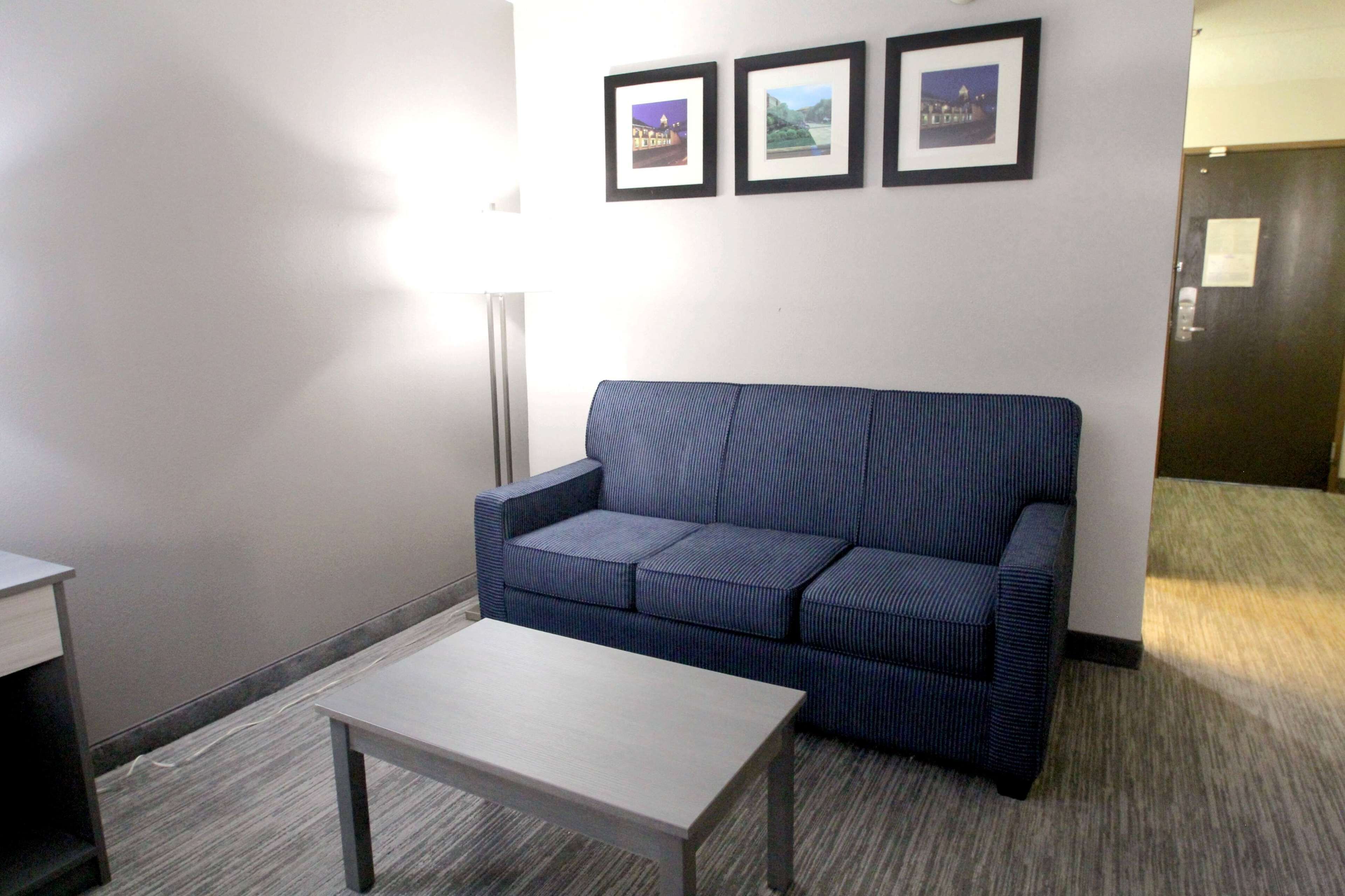 A room with a blue sofa, a small table, and three framed pictures on the wall.