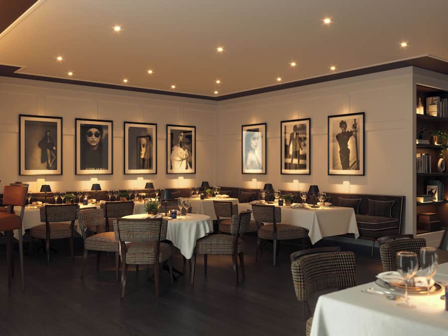 A restaurant with round tables, wicker chairs, and framed artwork on the walls.