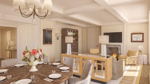 A spacious living room with a round dining table set for four, a fireplace, a television, and a comfortable seating area. - The Surrey A Corinthia Hotel (New York)