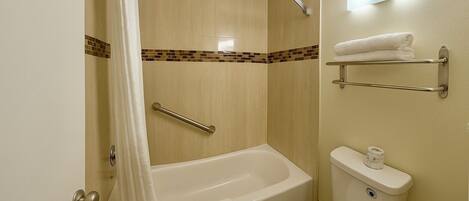 A bathroom with a bathtub, toilet, and a shower curtain.