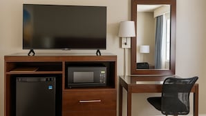 A hotel room with a flat-screen TV, a microwave, a mini fridge, a desk with a chair, and a mirror. - Days Inn by Wyndham Bradenton I-75 (Bradenton)