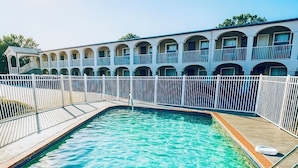 A swimming pool with a white fence, a brick border, and a building with balconies in the background. - Days Inn by Wyndham Bradenton I-75 (Bradenton)