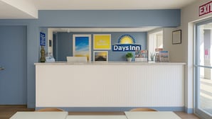 A reception desk with a Days Inn sign, framed pictures, a laptop, and informational brochures. - Days Inn by Wyndham Bradenton I-75 (Bradenton)