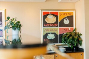 Una pared con un cartel de temática de café que muestra espresso, capuchino, moca y latte.