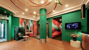 Een hal met een groene wand, een groot scherm en een receptiebalie.