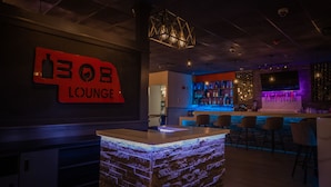 Una zona de bar con un letrero que dice "BOB LOUNGE", una barra y un área de estar con sillas.