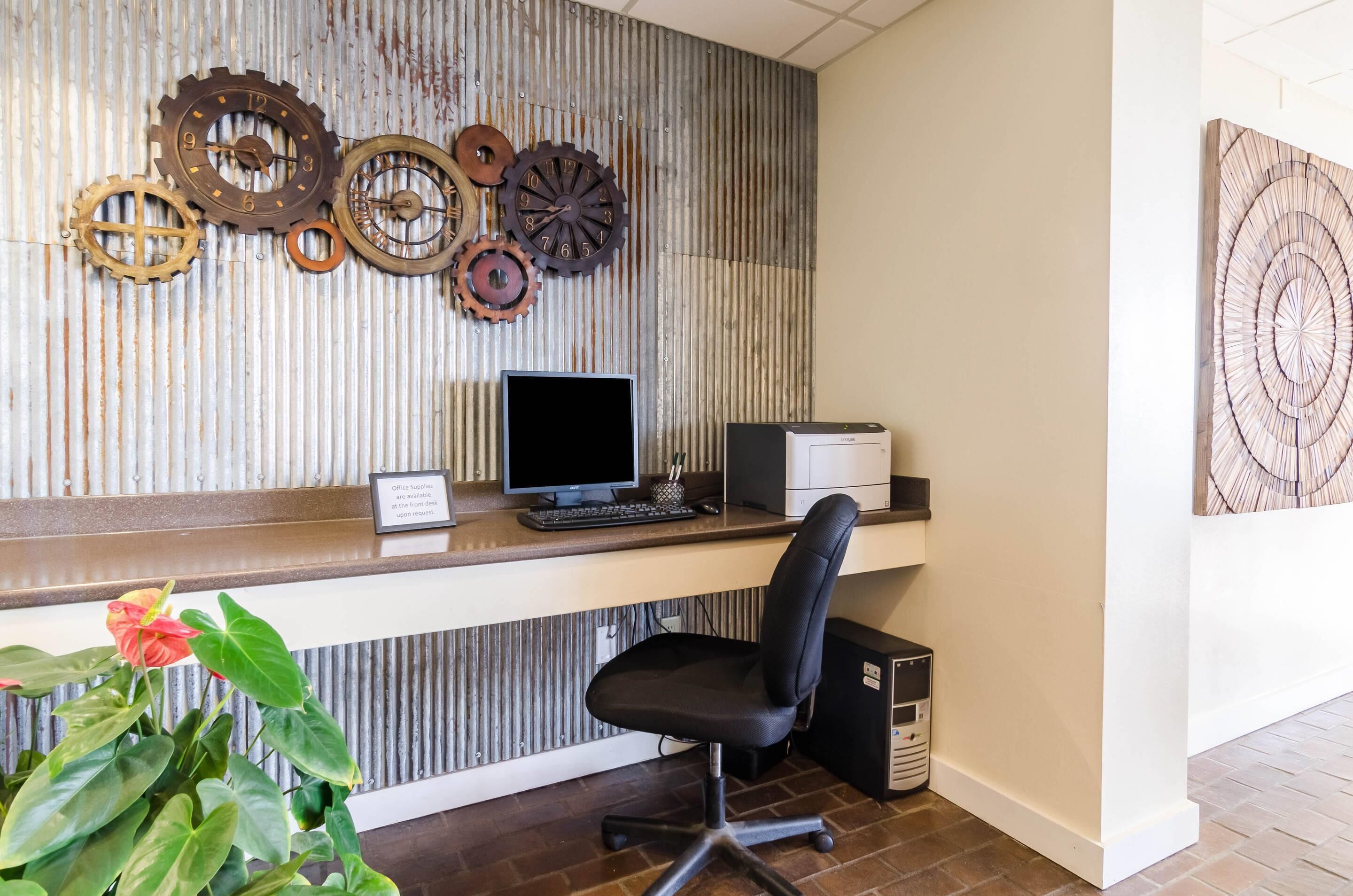 Ein Empfangsschalter mit Computer, Drucker und dekorativen Zahnrädern an der Wand.