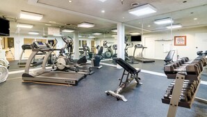 Un gimnasio con cintas de correr, elípticas y bancos de pesas.