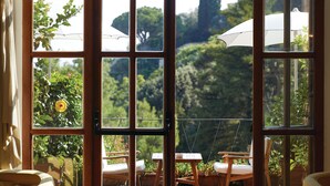 A room with a large arched window, a checkered floor, and a view of a garden with a swing chair and umbrella. - Splendido, A Belmond Hotel, Portofino (Portofino)