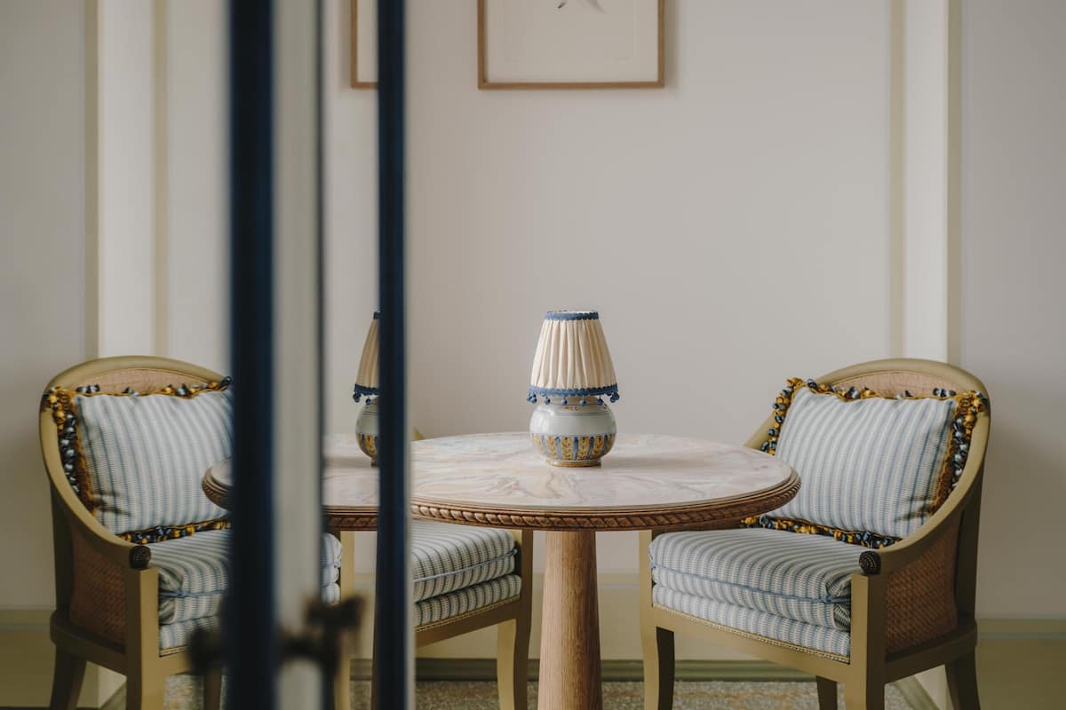 A round table with a vase and two upholstered chairs with patterned cushions.