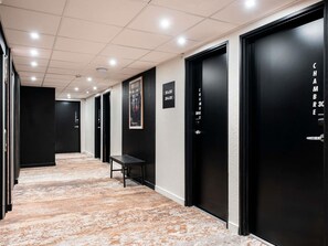 A hotel corridor with black doors, a bench, and a sign indicating room numbers. - ibis Styles Lyon Villeurbanne Parc de la Tête d'Or (Villeurbanne)