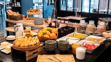 Un bufé con diversas opciones de comida, como pan, frutas y salsas.