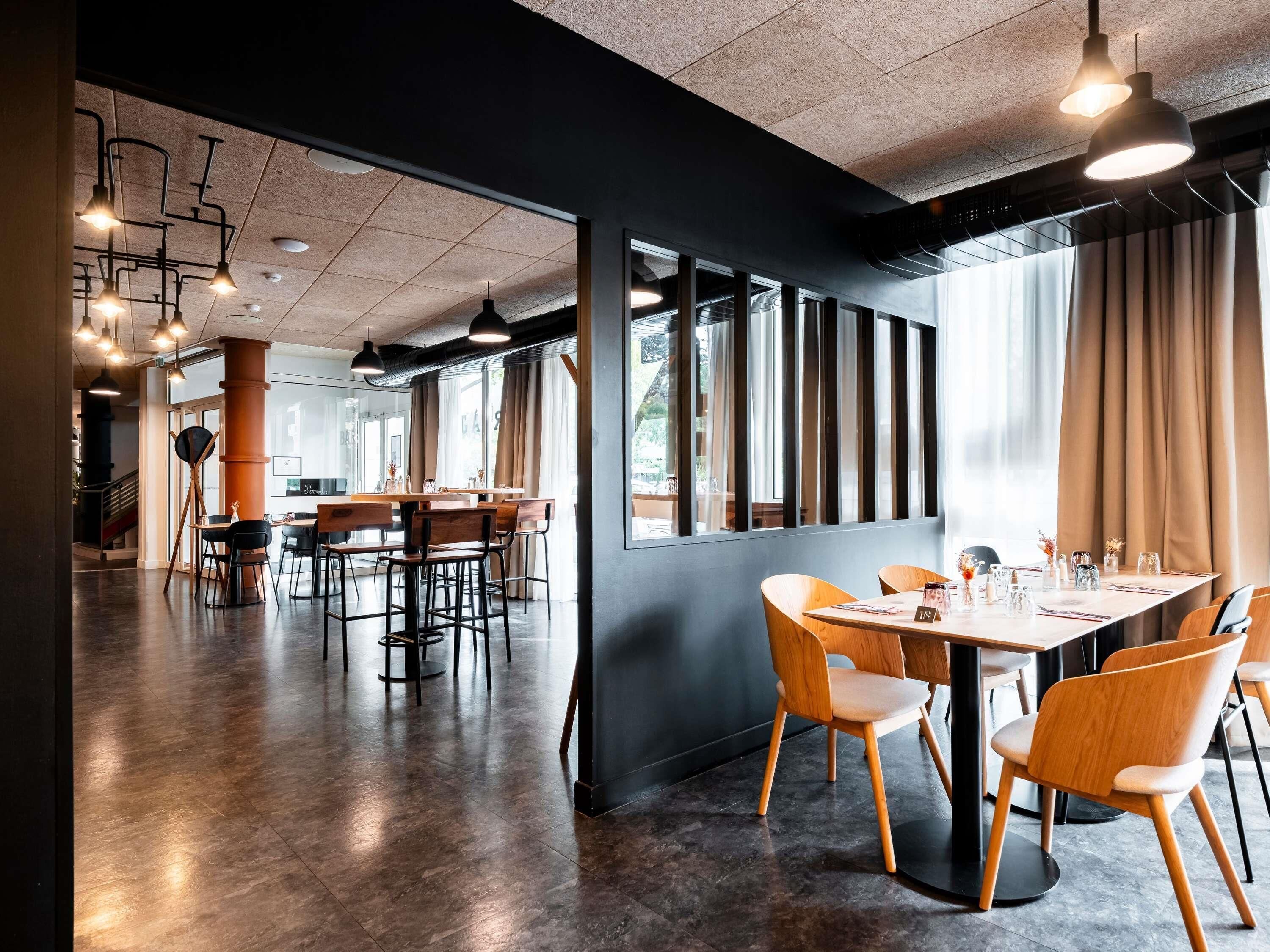 Um interior moderno com área de refeições, janelas amplas e iluminação estilo industrial.