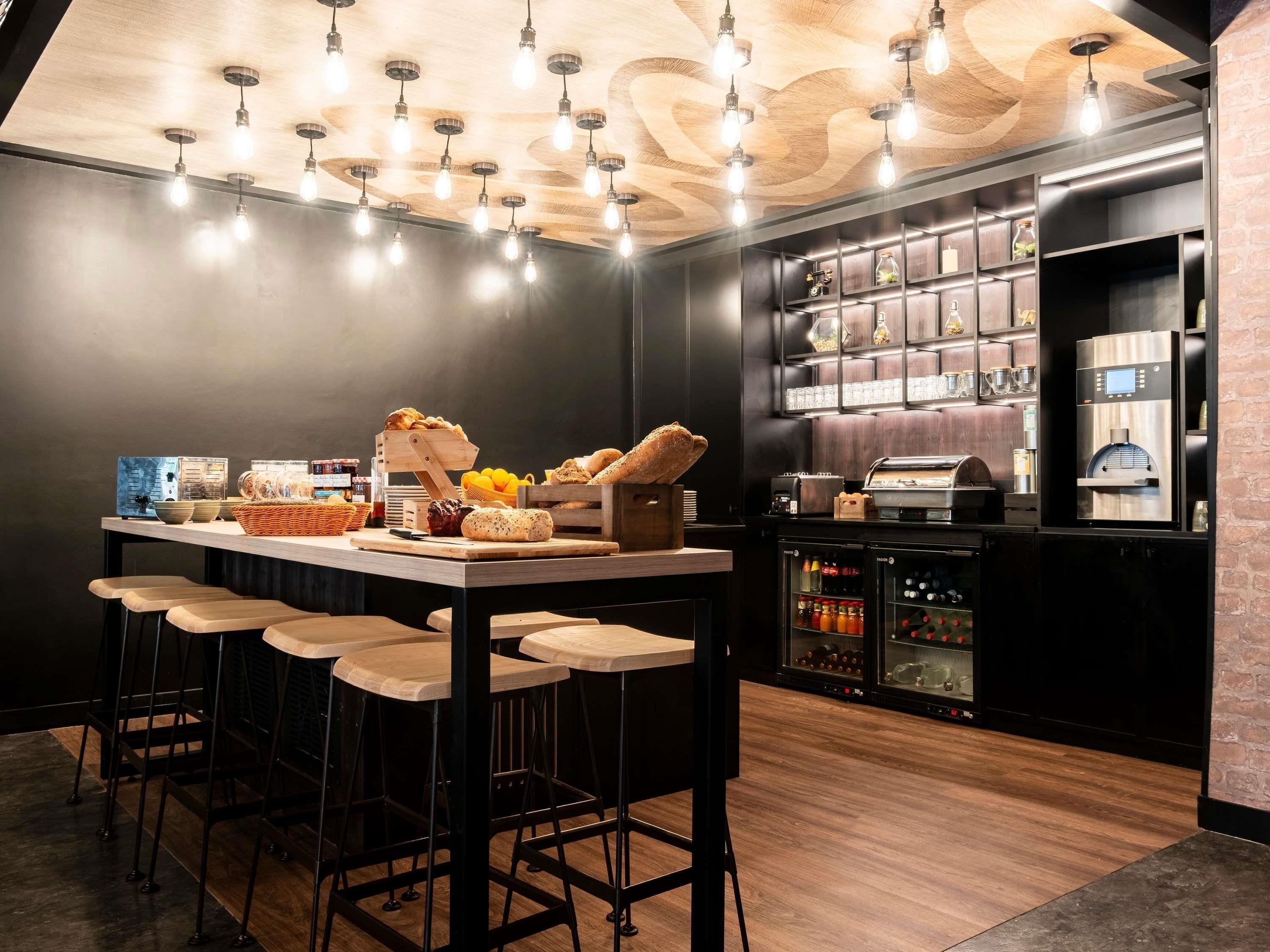 Angolo bar con soffitto in legno, sgabelli da bar, un bancone con prodotti alimentari e un frigorifero.