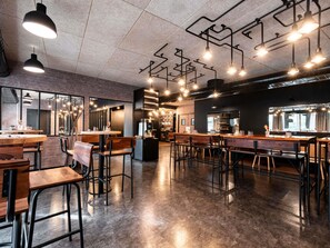 A modern cafe interior with exposed ductwork, wooden tables, and bar stools. - ibis Styles Lyon Villeurbanne Parc de la Tête d'Or (Villeurbanne)