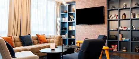 A modern living room with a sofa, armchairs, a coffee table, and a bookshelf.