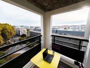 A balcony with a yellow table, a laptop, and a cup of coffee. - ibis Styles Lyon Villeurbanne Parc de la Tête d'Or (Villeurbanne)