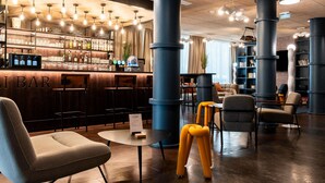 A bar area with a wooden counter, bar stools, and a seating area with chairs and a table.
