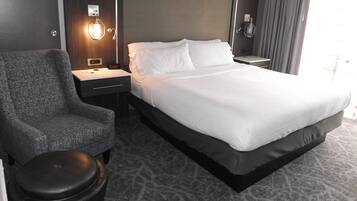 Una habitación de hotel con una cama, una silla, una mesita de noche y una lámpara.