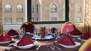 A table set for a meal with red napkins, clear glasses, and plates, viewed through a window with a view of a brick building. - Holiday Inn Downtown Memphis by IHG (Memphis)