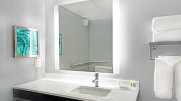 Un baño moderno con un lavabo blanco, un espejo grande y un perchero para toallas.